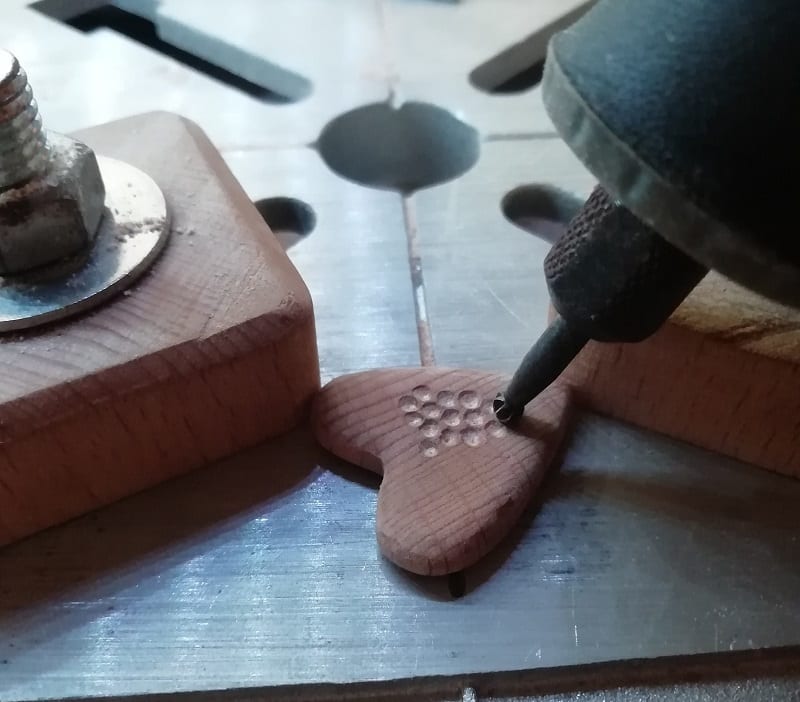 Use the high-speed carving bit of your Dremel tool to carve small dimples on one side of the pendant. 