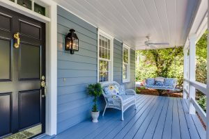 An image of a house front porch with a hanging bench.