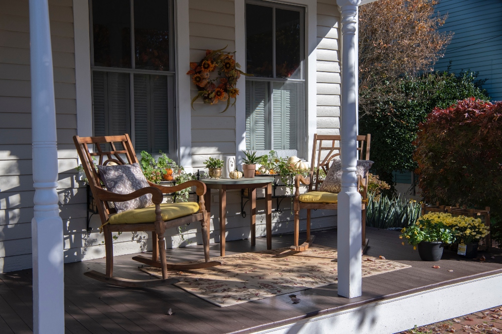 An image of a front porch with two rocking chairs and a table. 