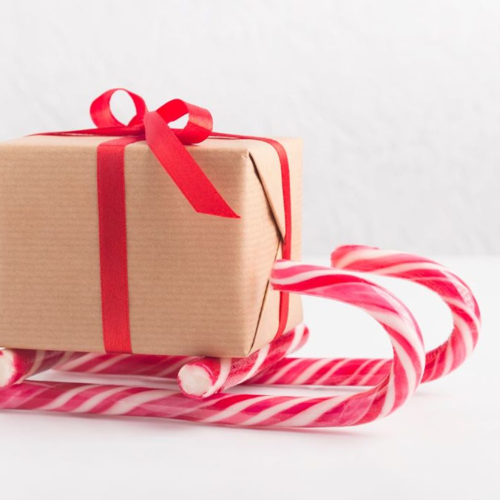 An image of a recycled paper wrapped gift box on top of candy canes. 